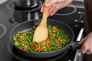 Photo of Woman cooking tasty vegetable mix in frying pan at home, closeup