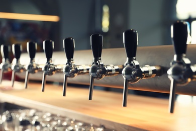 Row of shiny beer taps in pub