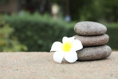 Photo of Stack of spa stones and beautiful flower outdoors, closeup. Space for text