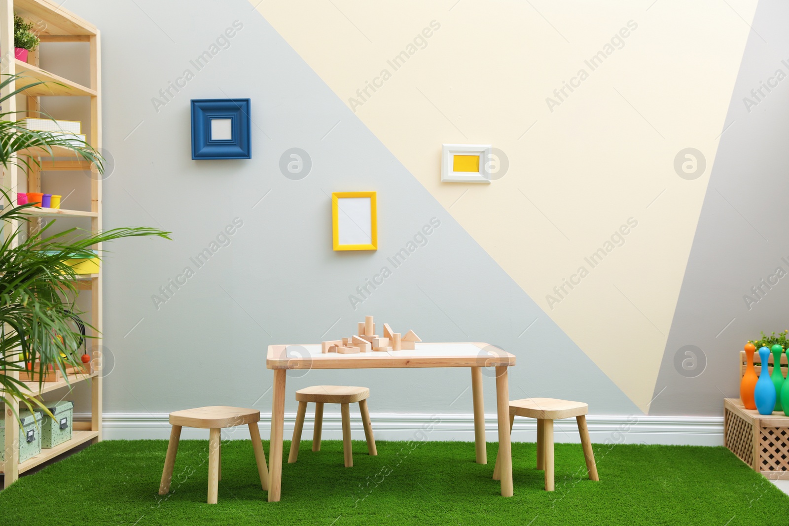 Photo of Stylish playroom interior with table, stools and green carpet