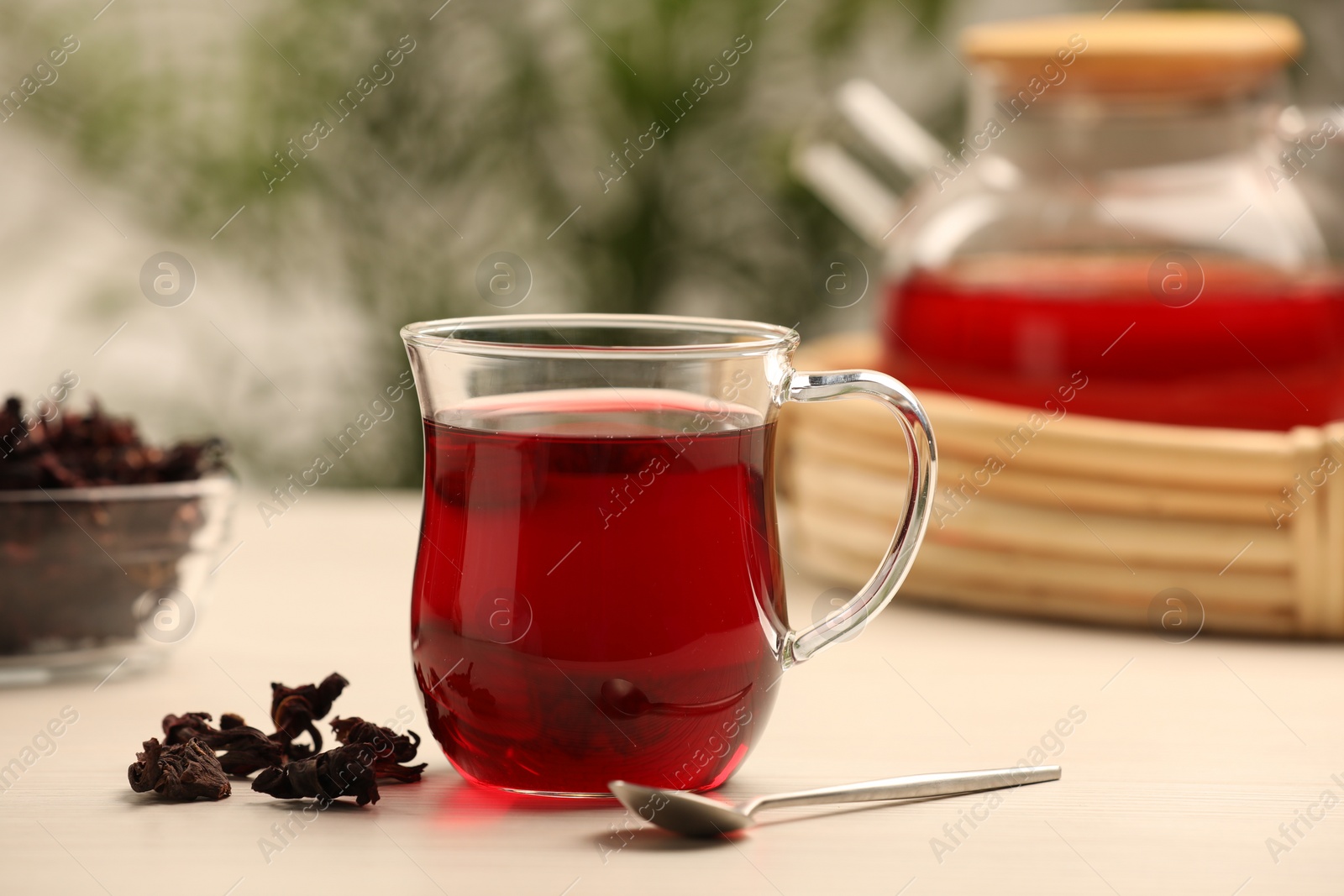 Photo of Delicious hibiscus tea and dry flowers on white wooden table