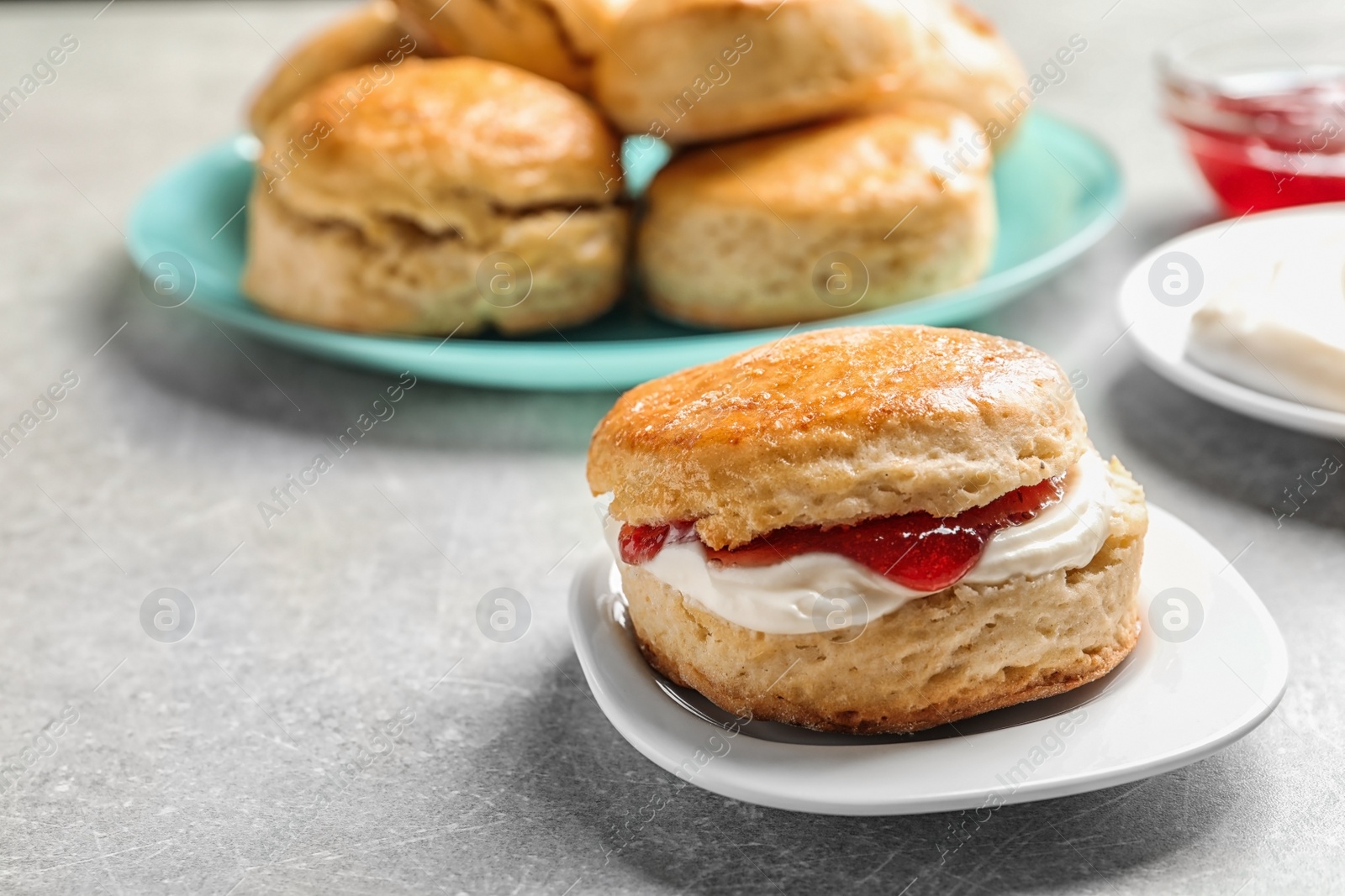 Photo of Tasty scone with clotted cream and jam on plate, closeup