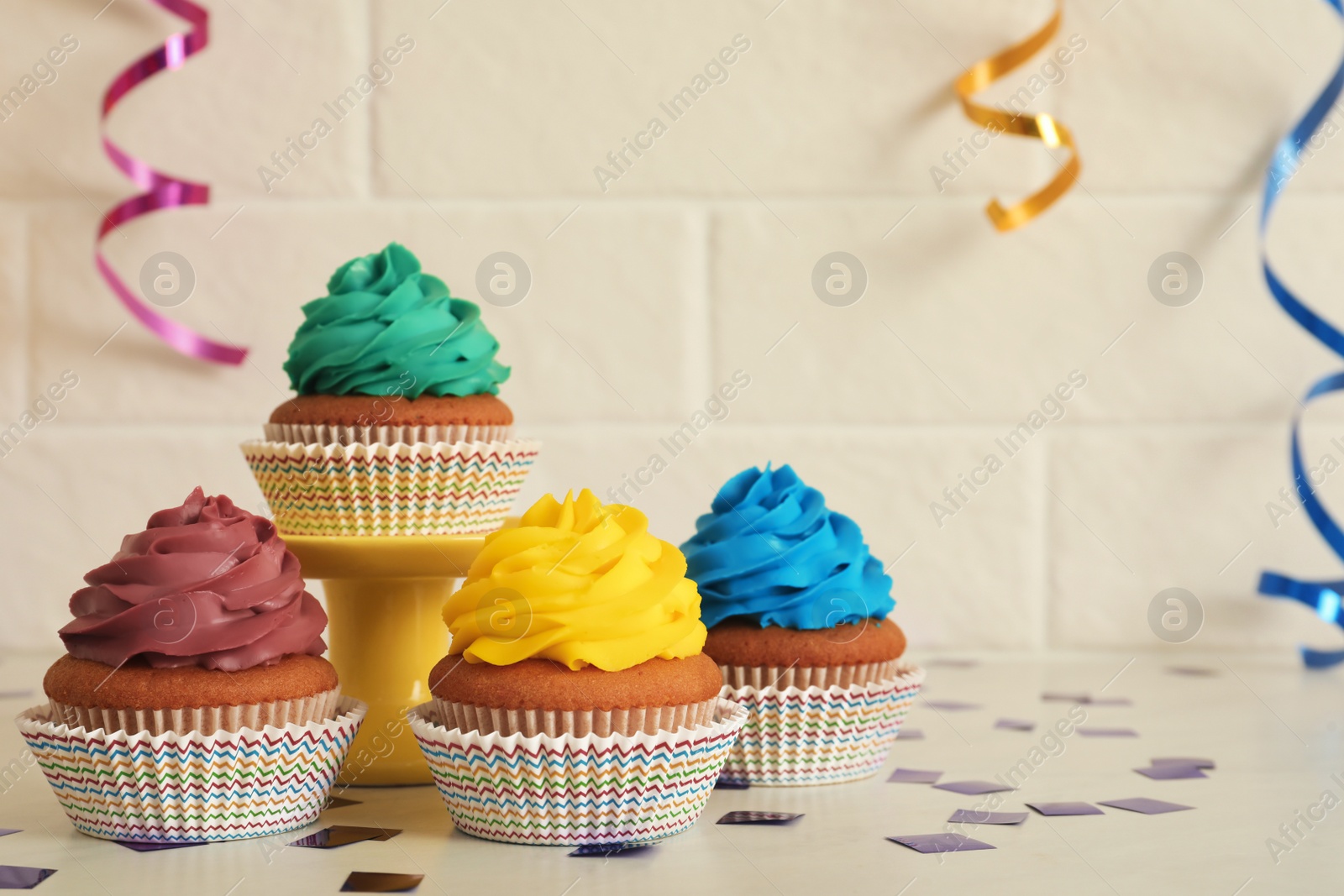 Photo of Delicious cupcakes with colorful cream on white table, space for text