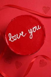 Bento cake with text Love You, ribbon and paper hearts on red table, flat lay. St. Valentine's day surprise