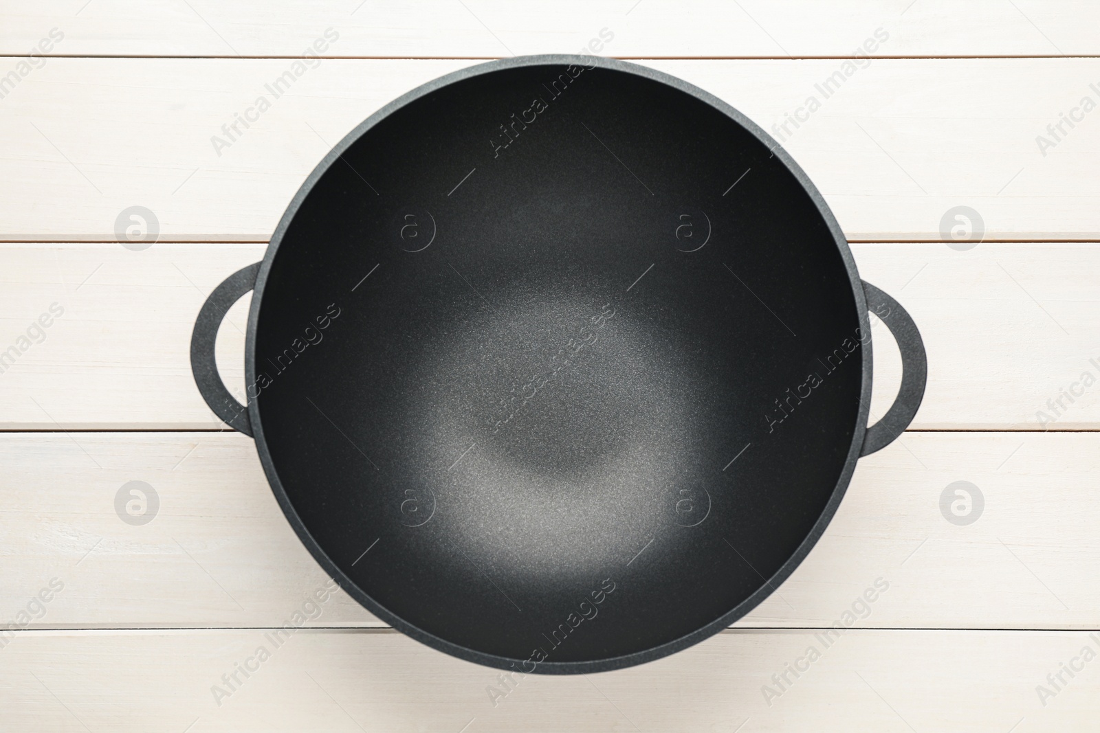 Photo of Empty iron wok on white wooden table, top view. Chinese cookware