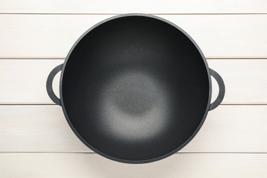 Photo of Empty iron wok on white wooden table, top view. Chinese cookware