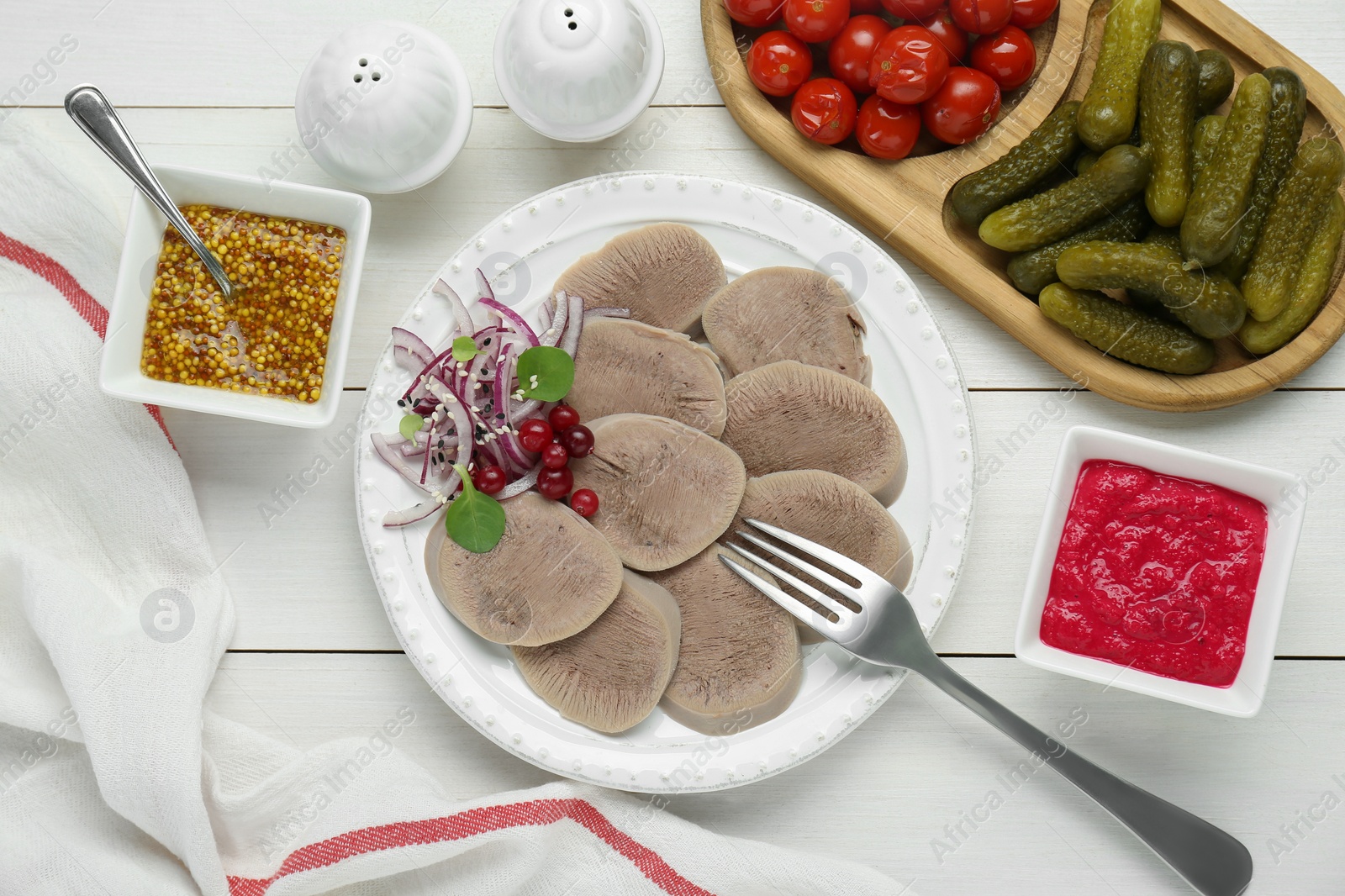 Photo of Tasty beef tongue pieces, berries, red onion and ingredients on white wooden table, flat lay