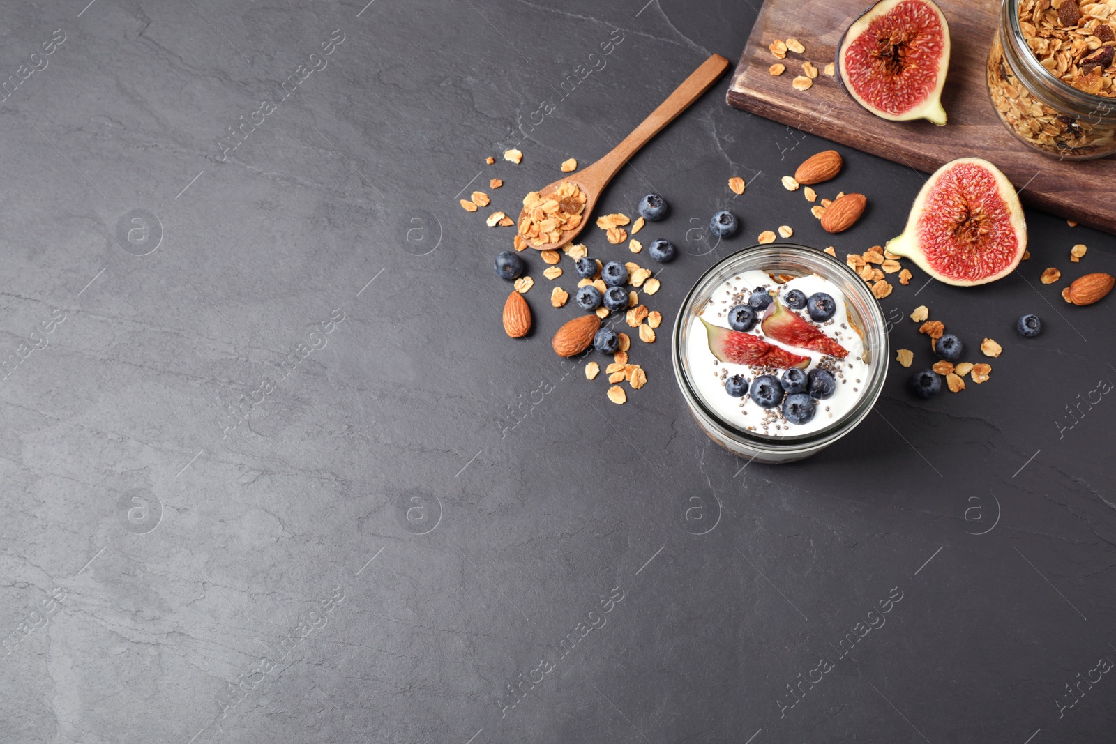 Photo of Healthy homemade granola with yogurt on dark grey table, flat lay. Space for text