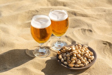 Glasses of cold beer and pistachios on sandy beach