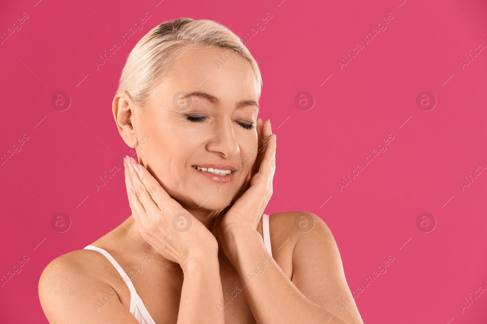 Photo of Portrait of beautiful mature woman on pink background. Space for text