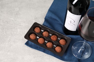Photo of Red wine and chocolate truffles on light textured table. Space for text