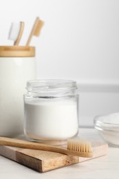 Photo of Bamboo toothbrushes and jar of baking soda on white table