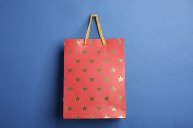 Photo of Red shopping paper bag with star pattern on blue background