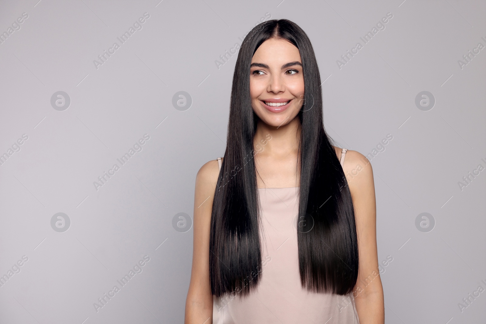 Photo of Portrait of beautiful young woman with healthy strong hair on light grey background, space for text