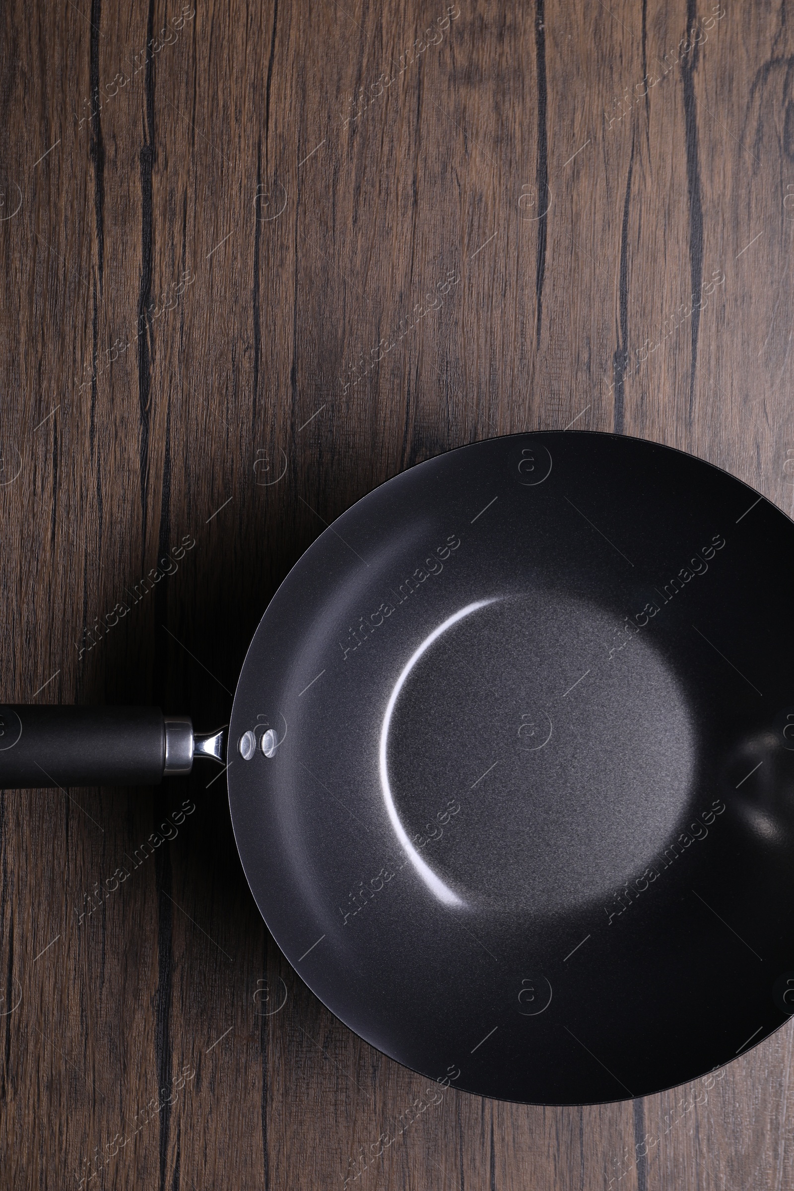 Photo of Empty iron wok on wooden table, top view. Chinese cookware