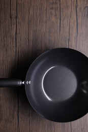 Empty iron wok on wooden table, top view. Chinese cookware