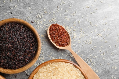 Photo of Flat lay composition with brown and other types of rice on grunge background. Space for text