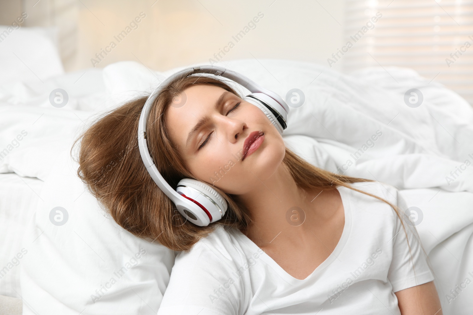 Photo of Lazy young woman with headphones sleeping in bedroom