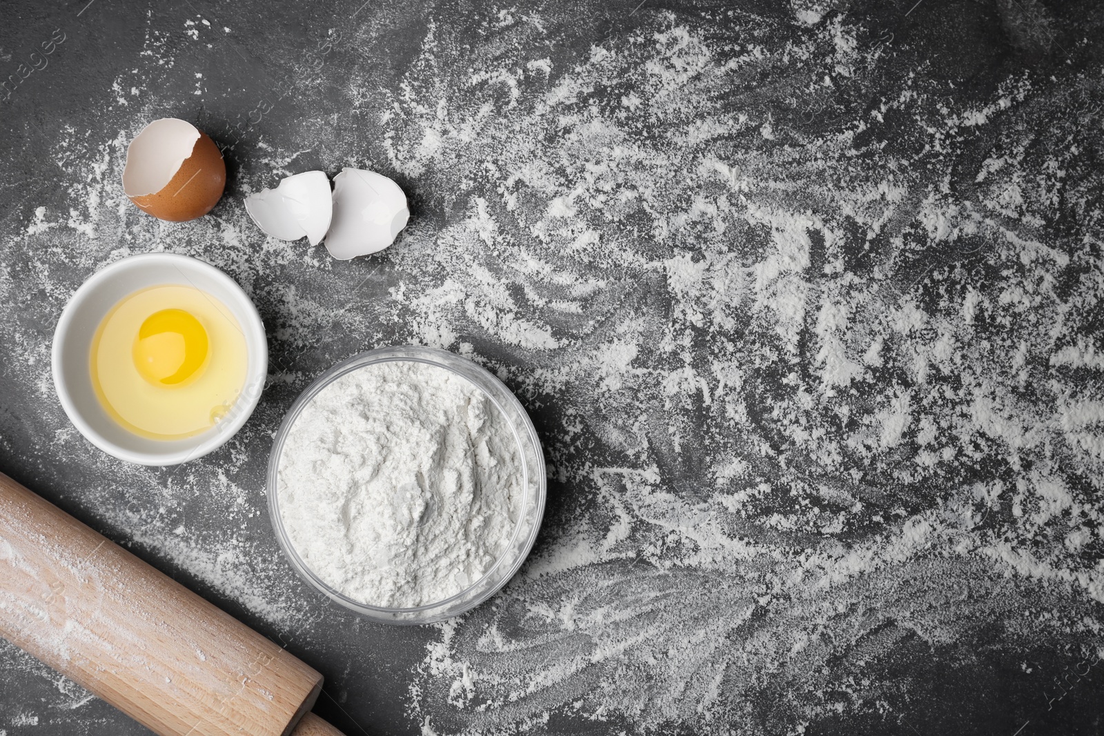 Photo of Bowl with flour and egg on grey background, top view