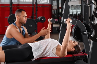 Trainer explaining woman how to do exercise properly in modern gym