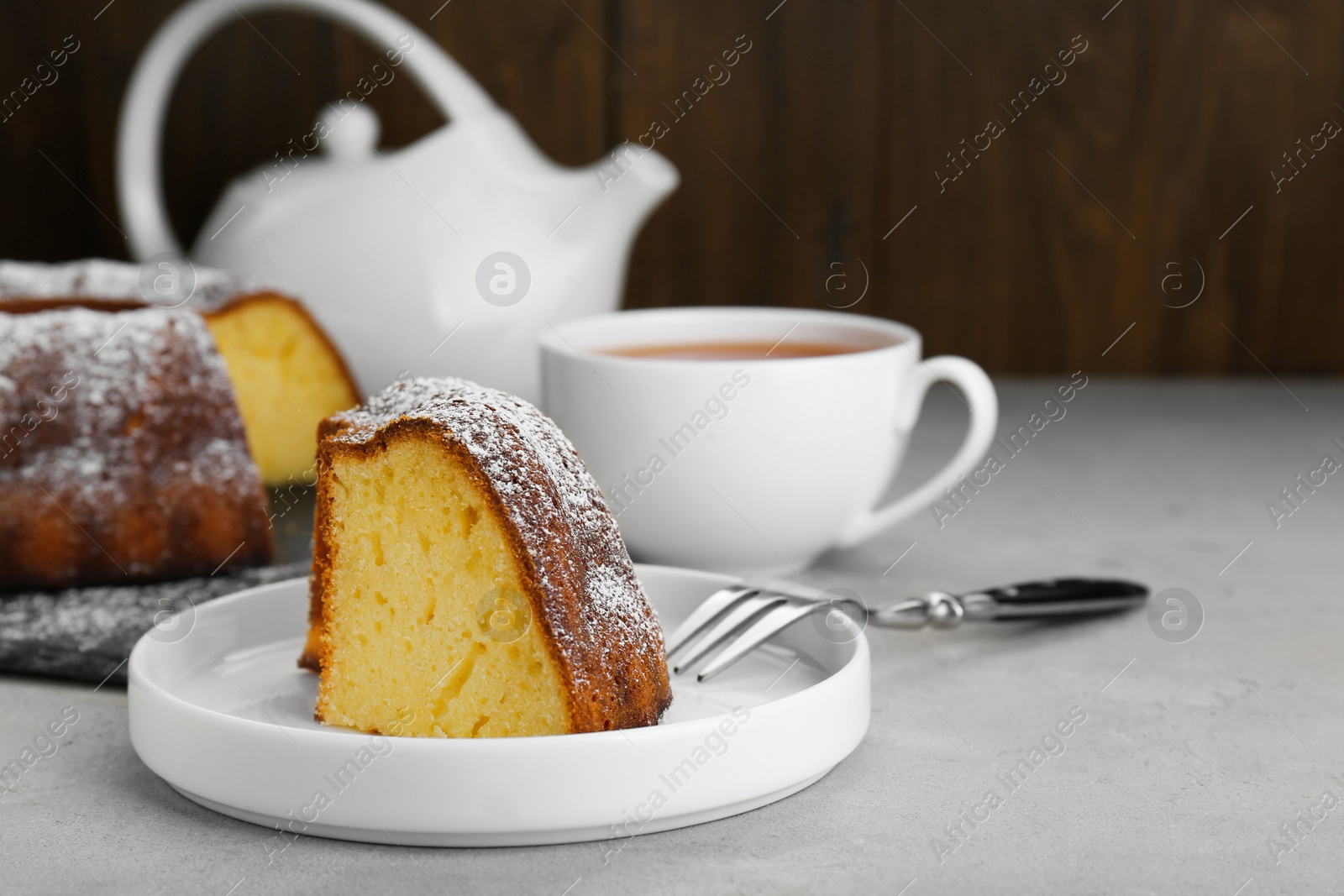 Photo of Piece of homemade yogurt cake with powdered sugar on light grey table. Space for text