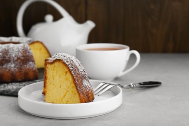 Piece of homemade yogurt cake with powdered sugar on light grey table. Space for text