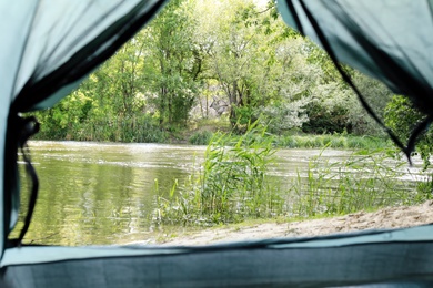 Photo of Calm river with forest on bank, view from camping tent
