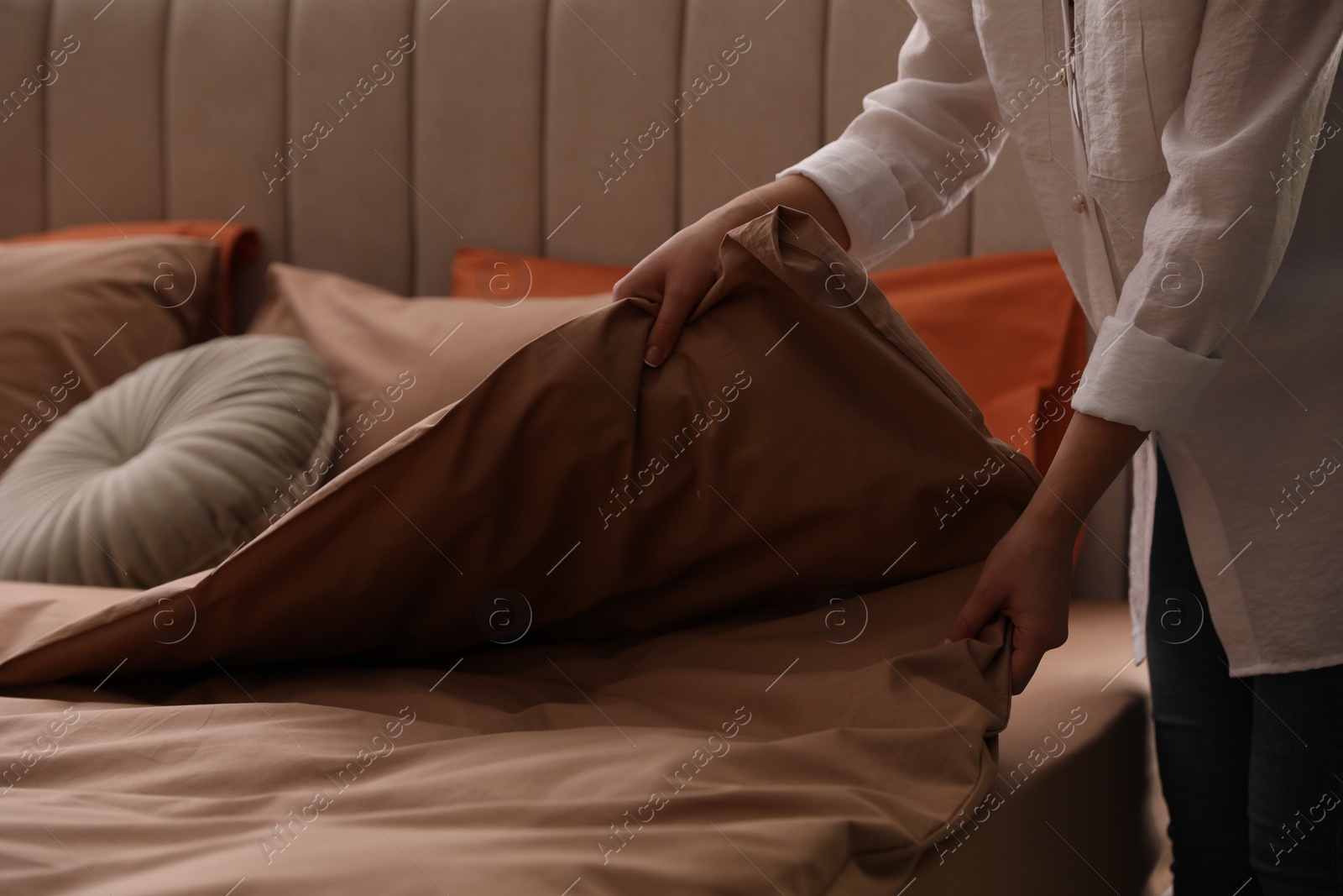 Photo of Woman making bed with stylish linens in room, closeup