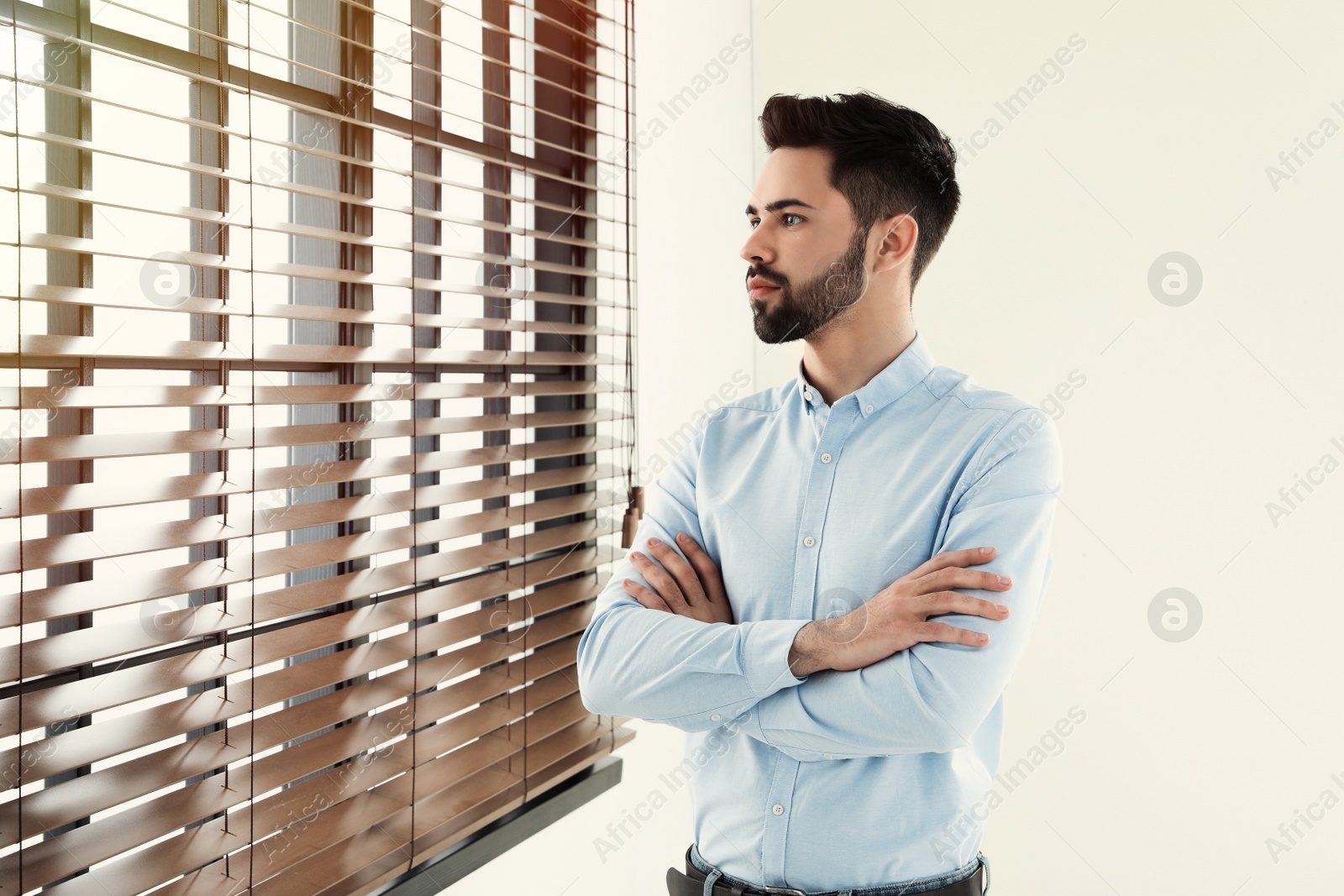 Photo of Portrait of handsome man at window indoors. Space for text