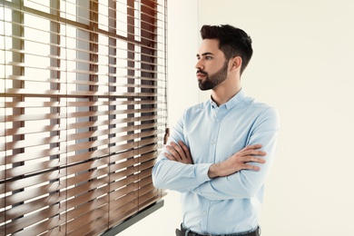 Portrait of handsome man at window indoors. Space for text