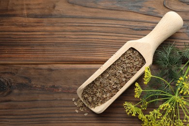 Scoop of dry seeds and fresh dill on wooden table, flat lay. Space for text