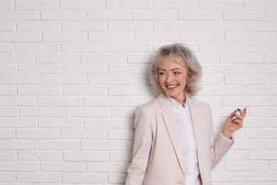 Photo of Portrait of mature woman near brick wall. Space for text