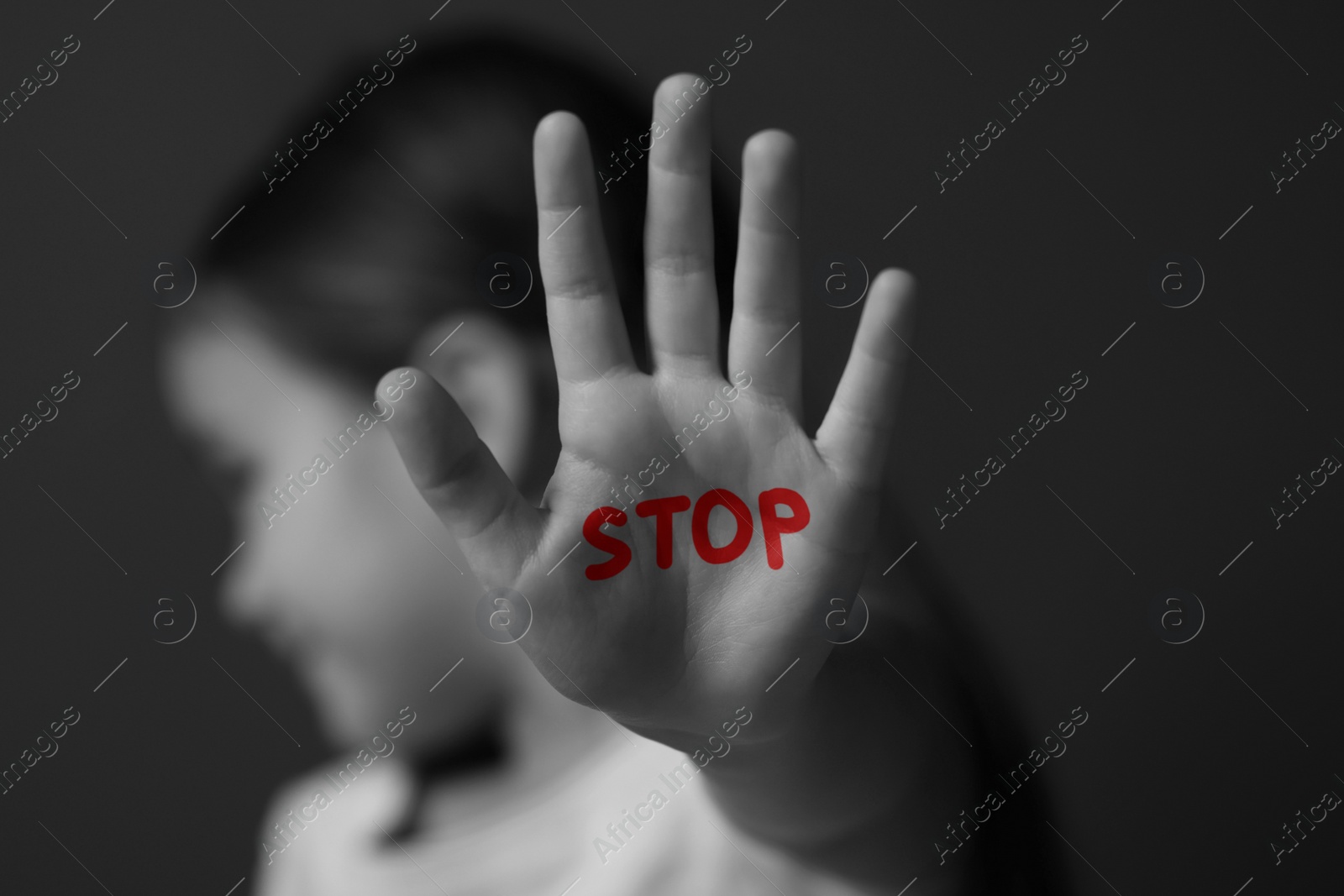Image of No child abuse. Girl showing hand with written Stop on palm, selective focus. Black and white effect
