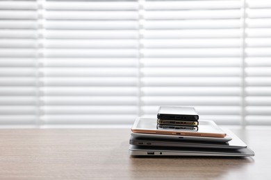 Many different modern gadgets on wooden table indoors. Space for text