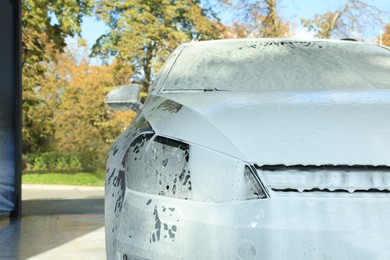 Photo of Auto with cleaning foam at car wash, closeup. Space for text
