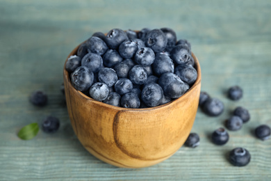 Photo of Fresh ripe blueberries in bowl on wooden table, closeup