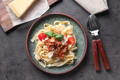 Photo of Plate with delicious pasta bolognese on grey background, top view