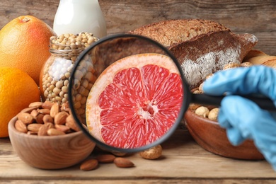 Different products with magnifier focused on grapefruit, closeup. Food allergy concept