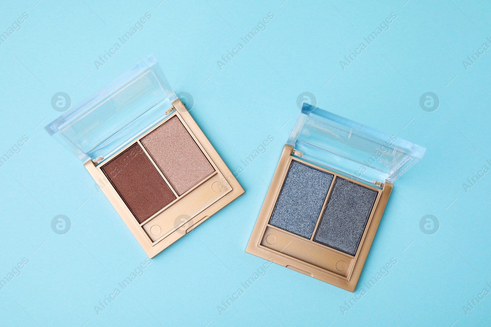 Photo of Beautiful eye shadow palettes on light blue background, flat lay