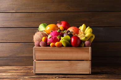Crate with different exotic fruits on wooden table