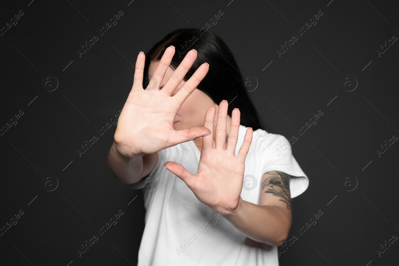 Photo of Young woman making stop gesture against dark background, focus on hand