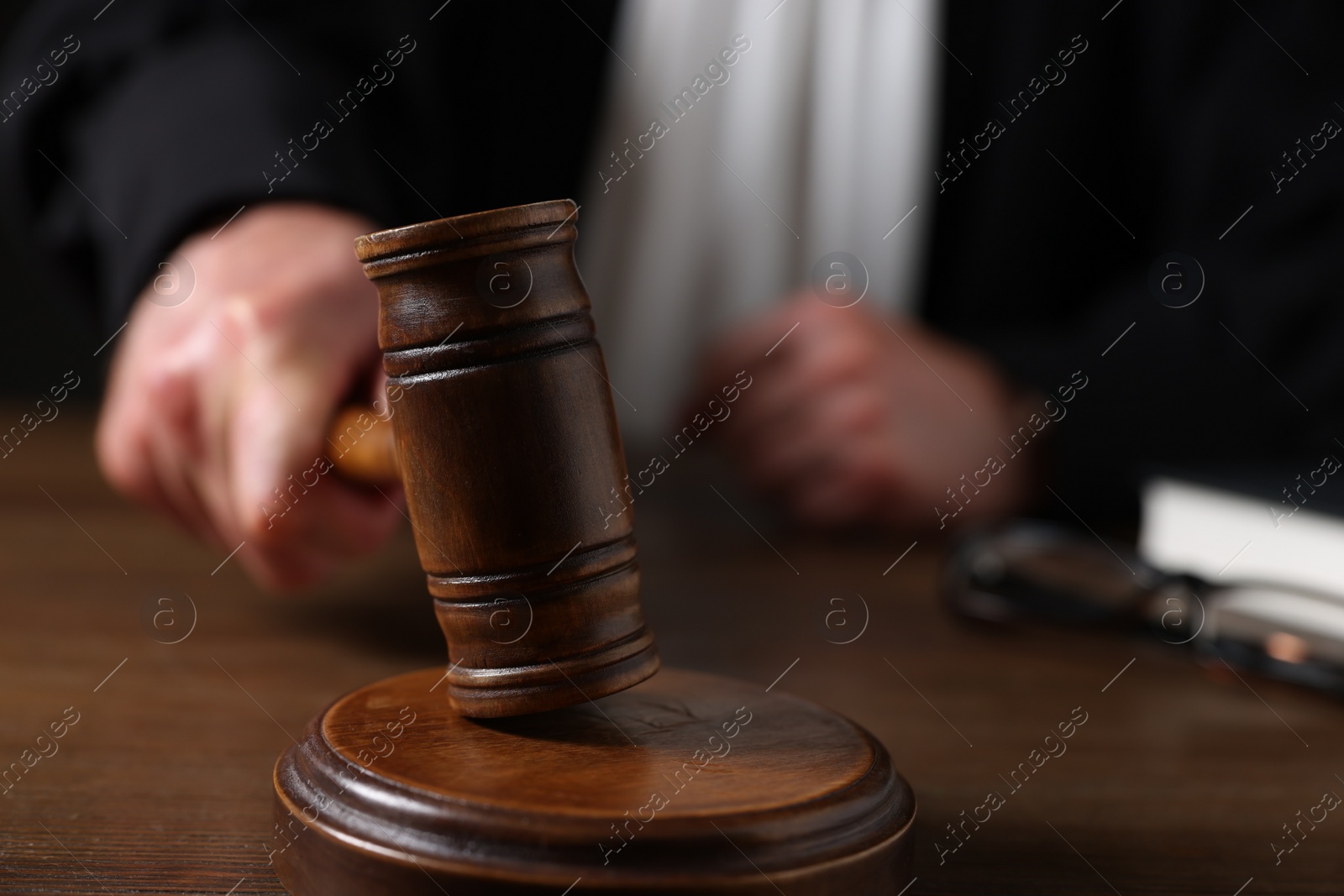 Photo of Judge with gavel sitting at wooden table, closeup