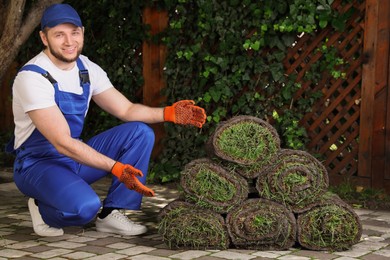 Photo of Gardener with grass sod rolls on backyard