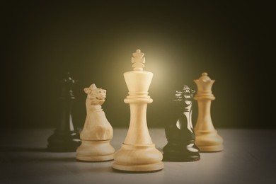 Image of Different chess pieces on grey table against dark background