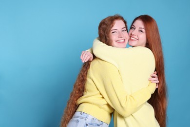 Photo of Portrait of beautiful young redhead sisters on light blue background. Space for text