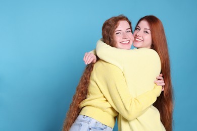 Portrait of beautiful young redhead sisters on light blue background. Space for text