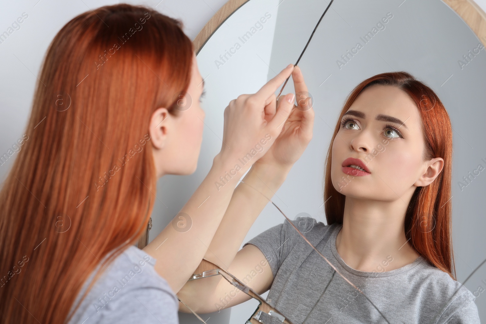 Photo of Sad young woman suffering from mental problems near broken mirror indoors