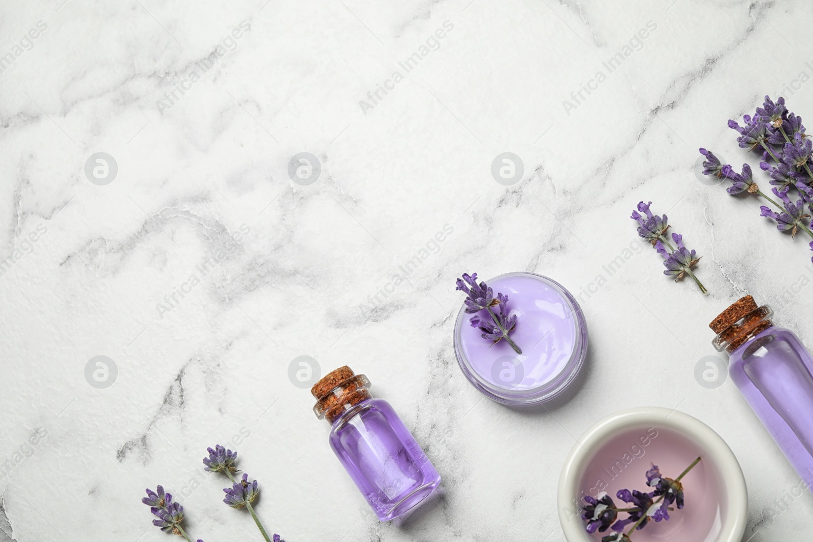 Photo of Cosmetic products and lavender flowers on white marble table, flat lay. Space for text