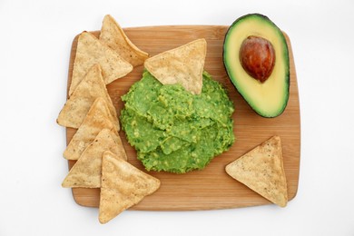 Delicious guacamole made of avocados, nachos and cut fruit on white background, top view