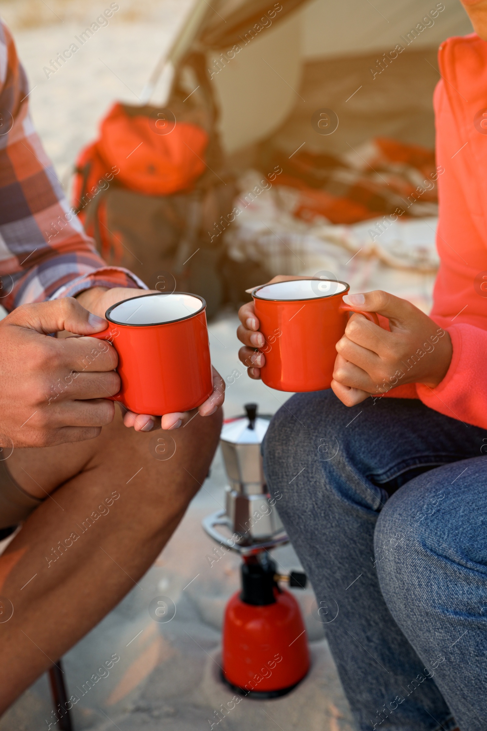 Photo of Couple with cups of hot drinks outdoors, closeup. Beach camping